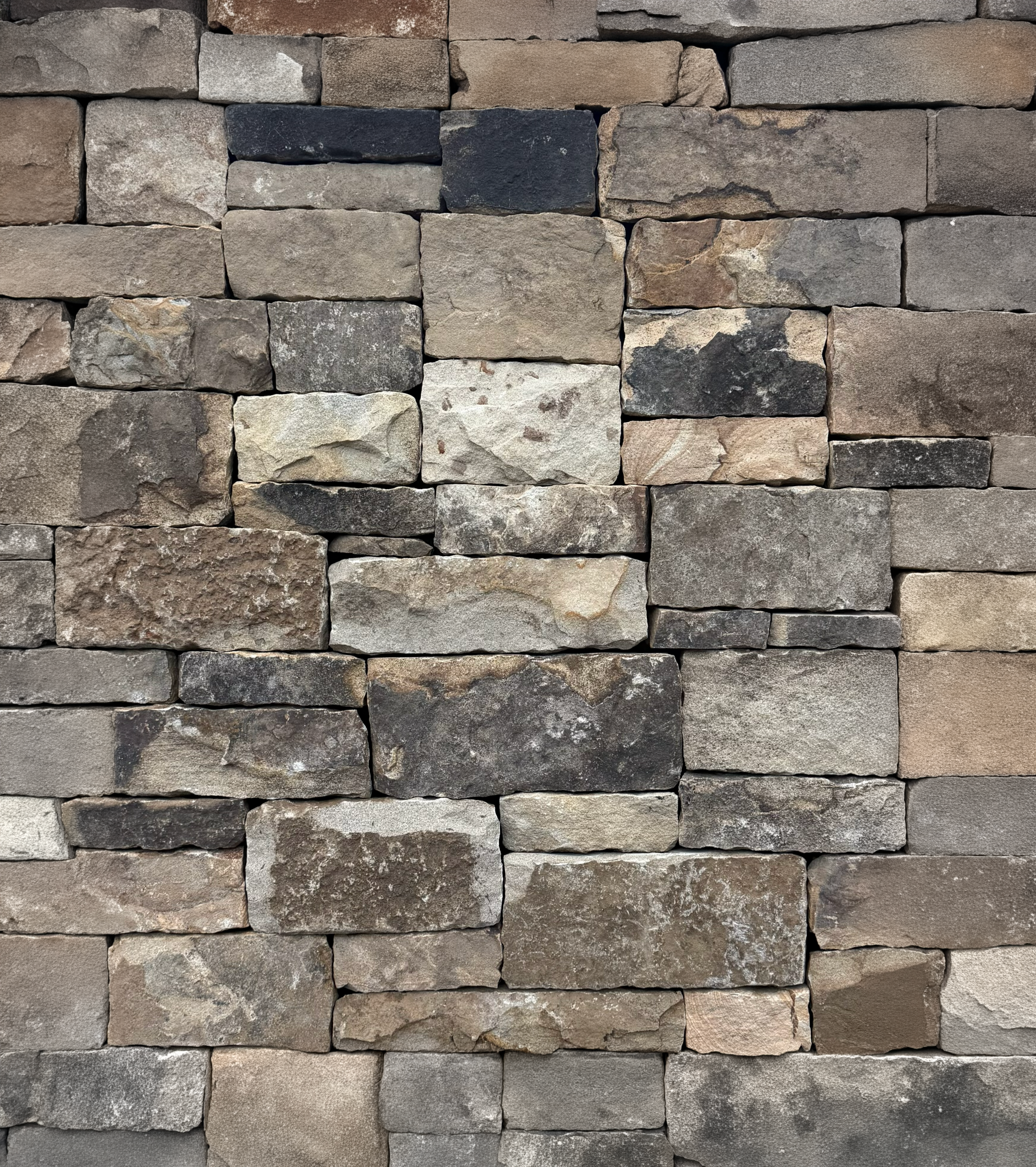 Actual Henderson natural stone veneer showing smoky charcoal, weathered gray, taupe, and warm brown tones